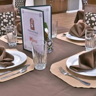 A neatly arranged restaurant table with brown napkins and glassware.