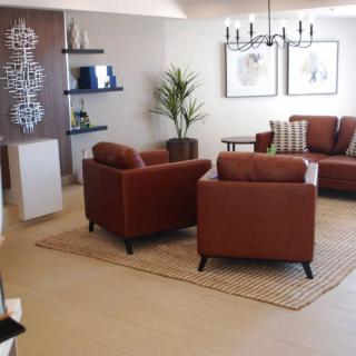 A modern living room featuring brown leather armchairs and a sofa, complemented by a stylish rug and decorative elements.