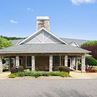 A well-maintained house with stone exterior and a chimney, surrounded by landscaped greenery.