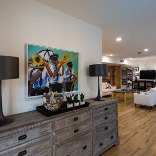 A modern living room with a wooden dresser, featuring abstract artwork and stylish lamps.