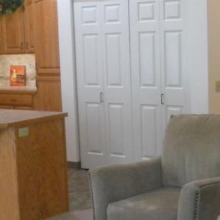 A cozy living room corner featuring a plush armchair, a kitchen counter, and white closet doors.