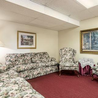 A traditionally decorated living room with floral furniture and paintings on the walls.