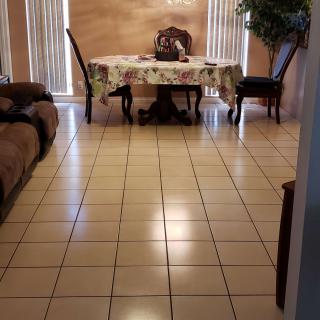 A cozy living room with a dining area featuring tile flooring, a sofa, and a table with chairs.
