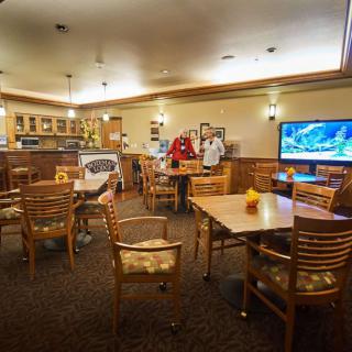 A cozy restaurant interior featuring a dining area with tables, chairs, and a television.