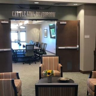 An open conference room with a table and chairs, seen through a welcoming lobby area.