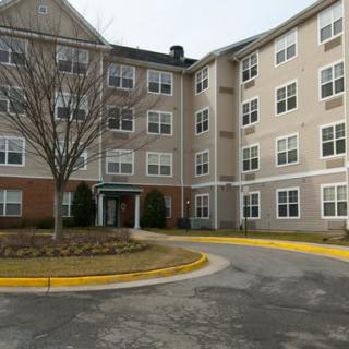 A multi-story residential apartment building with a parking area in front.