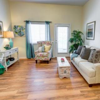 A cozy living room with a sofa, armchair, and coffee table on a hardwood floor.