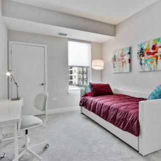 A modern minimalist bedroom with a single bed, desk, and colorful artwork.
