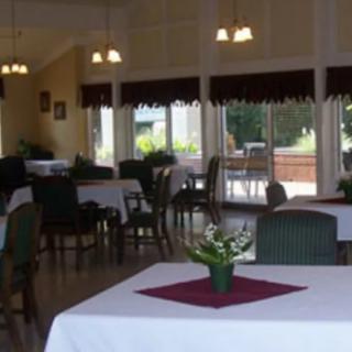 A spacious dining area with neatly arranged tables and chairs, decorated with plants and soft lighting.