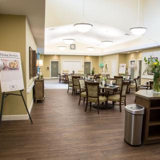 A spacious and elegantly designed dining area with neatly arranged tables and chairs, featuring stylish lighting and wood flooring.