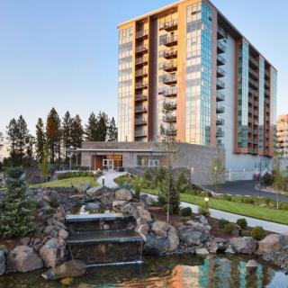A modern high-rise apartment building with landscaped gardens and a cascading water feature.