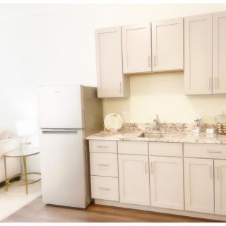 A modern kitchen with light-colored cabinets, a refrigerator, and a sink.