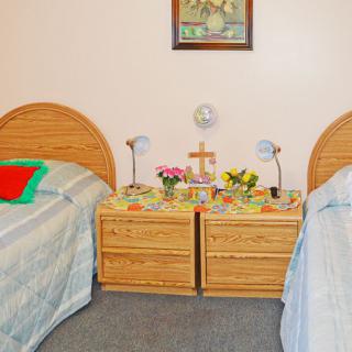 A cozy bedroom with twin beds and a shared nightstand adorned with lamps and flowers.