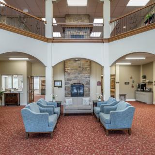 A spacious lobby with comfortable seating and a central fireplace.