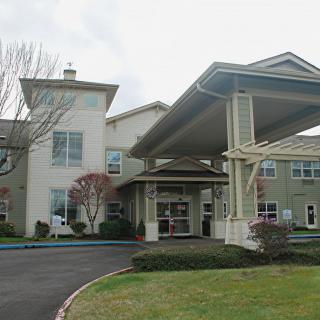 A building with a covered entrance and surrounding landscaped area.
