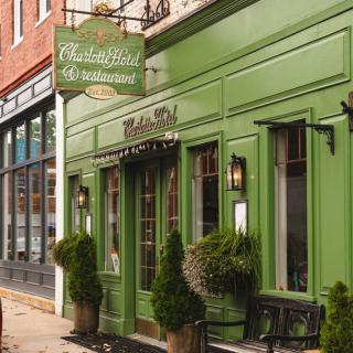 A quaint restaurant with a green facade and decorative plants at the entrance.