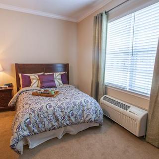 A cozy bedroom with a neatly made bed and natural light filtering through the window.