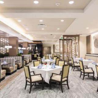 A modern restaurant dining area with neatly arranged tables and chairs, featuring elegant lighting and decor.