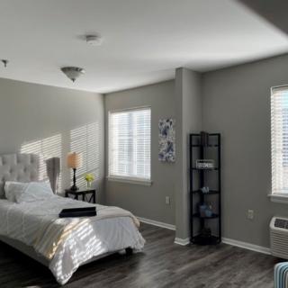 A modern, minimalist bedroom with white walls and natural light streaming through the windows.