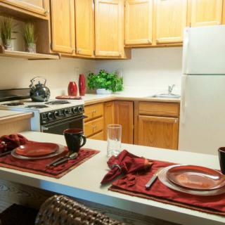 A cozy kitchen with a neatly set dining area, featuring wooden cabinets and modern appliances.