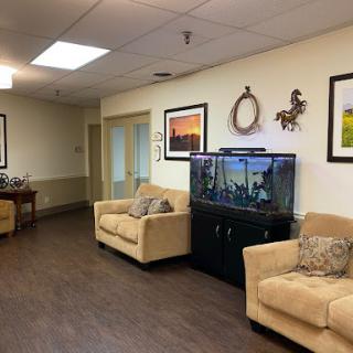 A cozy waiting area featuring soft sofas, an aquarium, and decorative photos on the walls.