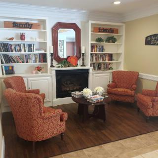 A cozy living room featuring four armchairs, a fireplace, and built-in bookshelves filled with books and decor.