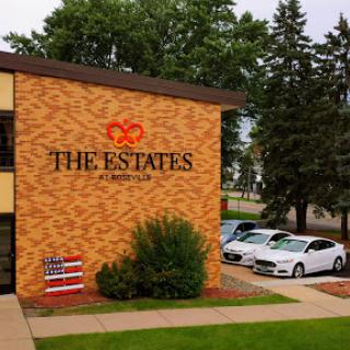 The Estates residential building featuring an American flag and parked cars.