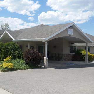A single-story building with a driveway and landscaped front, set against a cloudy sky.