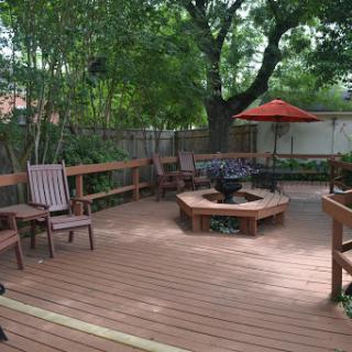 A cozy outdoor deck featuring a fire pit and comfortable seating, surrounded by lush greenery.