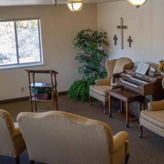 A cozy room with comfortable seating, a piano, and decorative crosses on the wall.