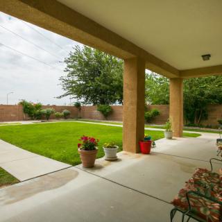 A spacious patio overlooks a well-manicured lawn and garden, featuring outdoor seating and decorative plants.
