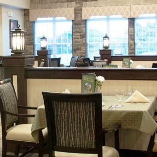 A cozy restaurant interior with a neatly set dining table and comfortable chairs.
