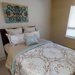 A cozy bedroom with elegant bedding and decorative wall art.