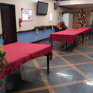 A festive indoor setting with tables covered in red tablecloths and a decorated Christmas tree.