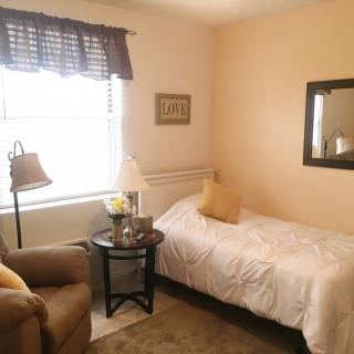 A cozy bedroom with a single bed, armchair, and decorative elements.