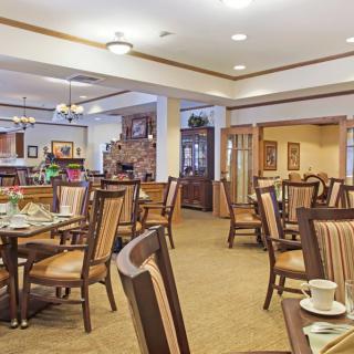 A cozy dining area with neatly arranged tables and chairs, softly lit by ceiling lights.
