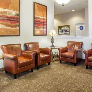 A cozy waiting area featuring leather armchairs and abstract artwork on the walls.