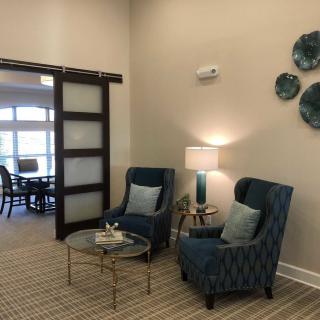 A cozy seating area with two armchairs and a coffee table, illuminated by a lamp.