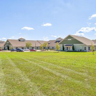 A suburban residential building with a large green lawn under a clear blue sky.