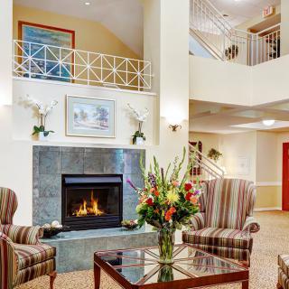 A cozy living area featuring a fireplace with striped armchairs and floral decor.