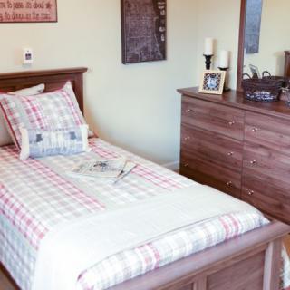 A cozy bedroom with a single bed and a wooden dresser.