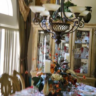 A beautifully decorated dining room with an elegant chandelier and a festive table setting.