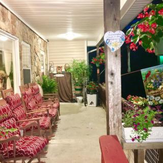 A cozy porch with patterned chairs, vibrant flowers, and ambient lighting at night.