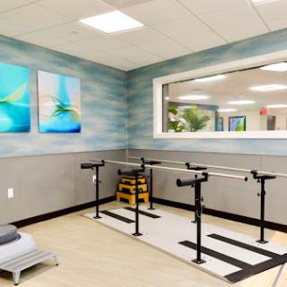 A well-equipped physical therapy studio featuring barre exercises and calming artwork.