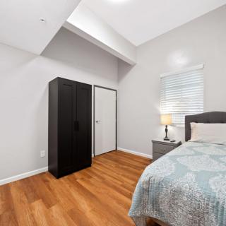 A modern bedroom with a bed, black wardrobe, and a lamp on a nightstand.