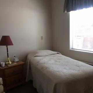 A minimalist bedroom with a single bed, nightstand, and window.