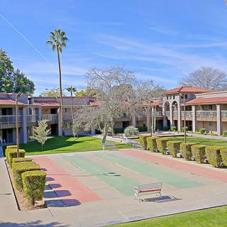 A sunny day at a courtyard of an apartment complex, featuring well-maintained landscaping and a palm tree.