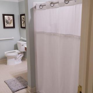 A clean bathroom with a white shower curtain and decorative artwork on the walls.