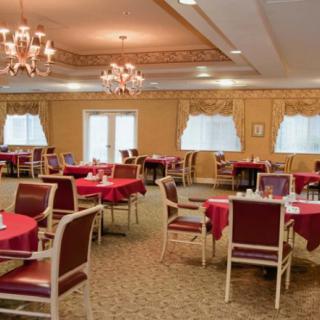 An elegant dining area with neatly arranged tables and chairs, decorated with chandeliers.