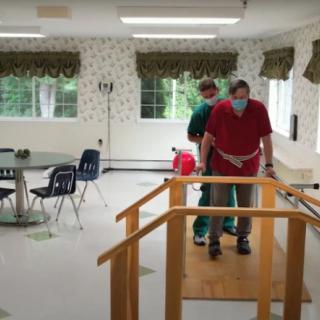 A healthcare professional assists a patient in a rehabilitation session using parallel bars.